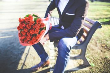 Junger Mann hält einen Strauß rote Rosen
